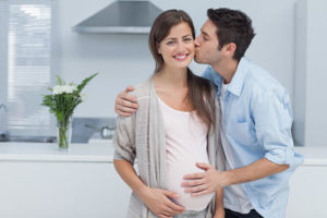 Man kissing his pregnant wife and touching his belly