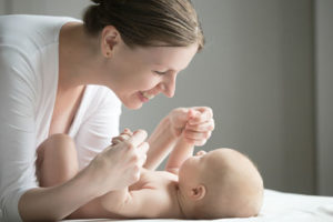 Portrait of a young beautiful woman playing with a newborn. Family concept photo, lifestyle