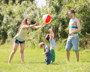 Smiling parents with children playing in park at sunny day