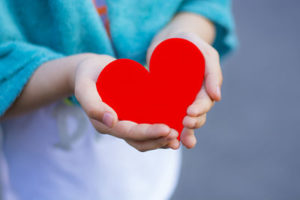 Little girl holding red heart in her hands.
