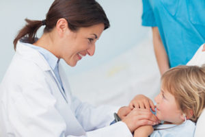 Doctor holding hands of a child in hospital ward