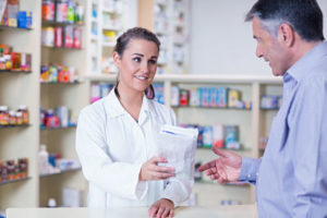 Trainee giving a bag of pills to a customer in a drugstore